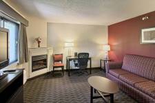 Traverse Blossom hotel Queen Two Room living area with couch, coffee table, TV, fireplace, desk, two chairs near desk