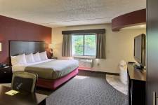 Traverse Blossom hotel King Whirlpool room with king bed, hot tub, TV, microwave, mini fridge, desk, chair, and wardrobe