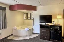 Traverse Blossom hotel King Whirlpool room with king bed, hot tub, TV, microwave, mini fridge, desk, chair, and wardrobe