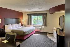 Traverse Blossom hotel King Whirlpool room with king bed, hot tub, TV, microwave, mini fridge, desk, chair, and wardrobe