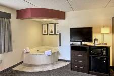 Traverse Blossom hotel King Whirlpool room with king bed, hot tub, TV, microwave, mini fridge, desk, chair, and wardrobe