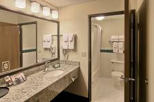 Traverse Blossom hotel King Whirlpool bathroom with standard tub/shower and toilet, sink in bedroom